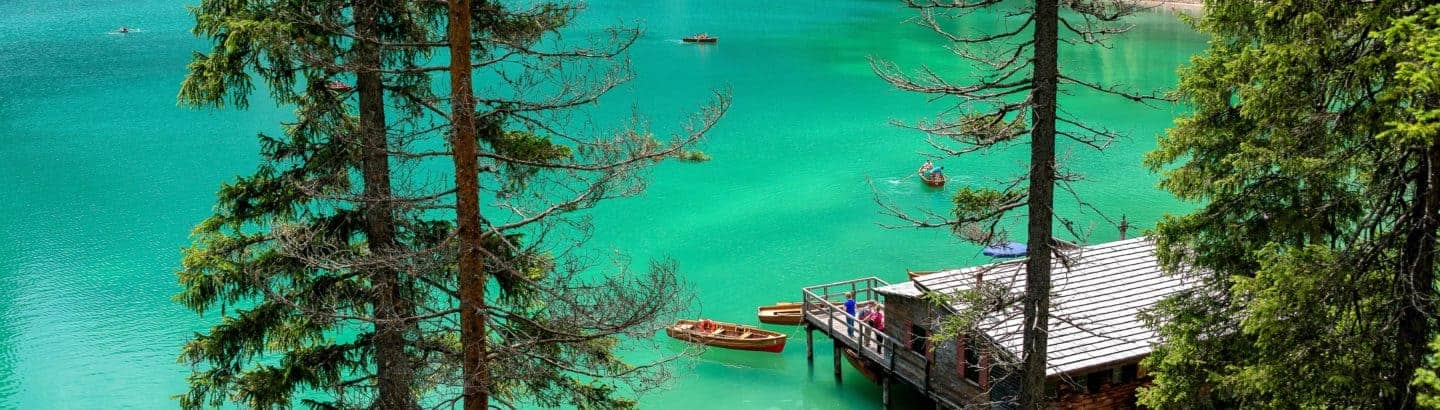 Tourismus Ziel an türkis-blauen See, mit Tannen, das auch eine Tourismus Übersetzung benötigt